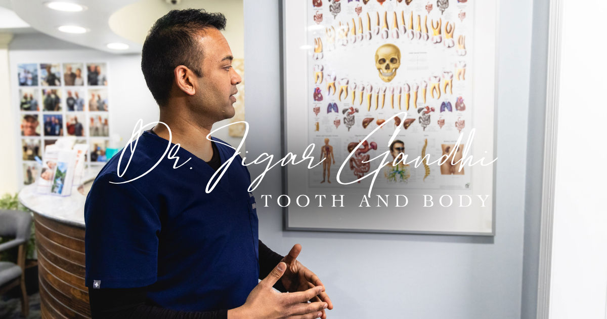 Man standing in a dental office, looking at a wall chart of teeth and mouth anatomy.