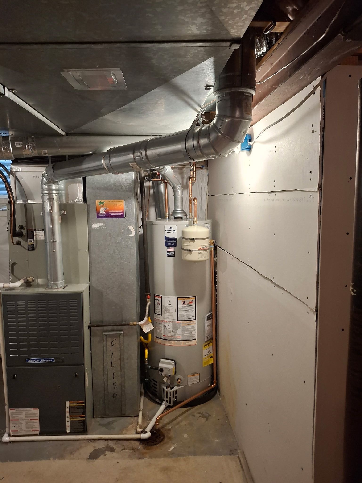 Basement utility room with water heater, furnace, and metal ductwork along the wall.