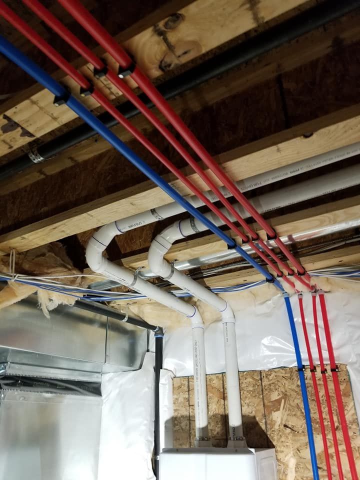 Exposed ceiling pipes and ducts in a basement under construction, with red and blue lines overhead