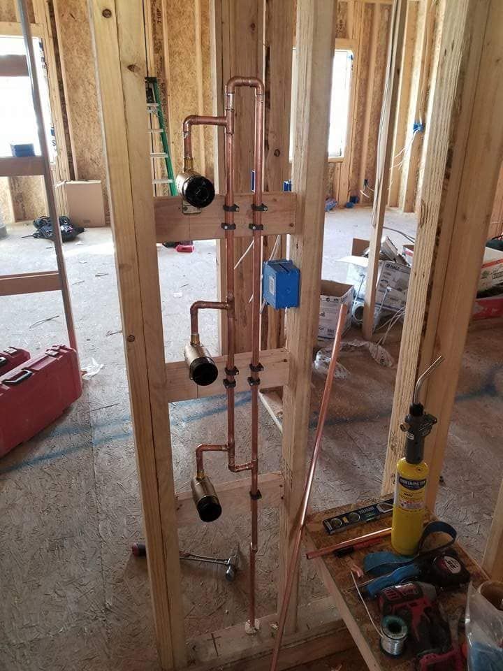 Copper plumbing pipes and valves installed in a framed house under construction.