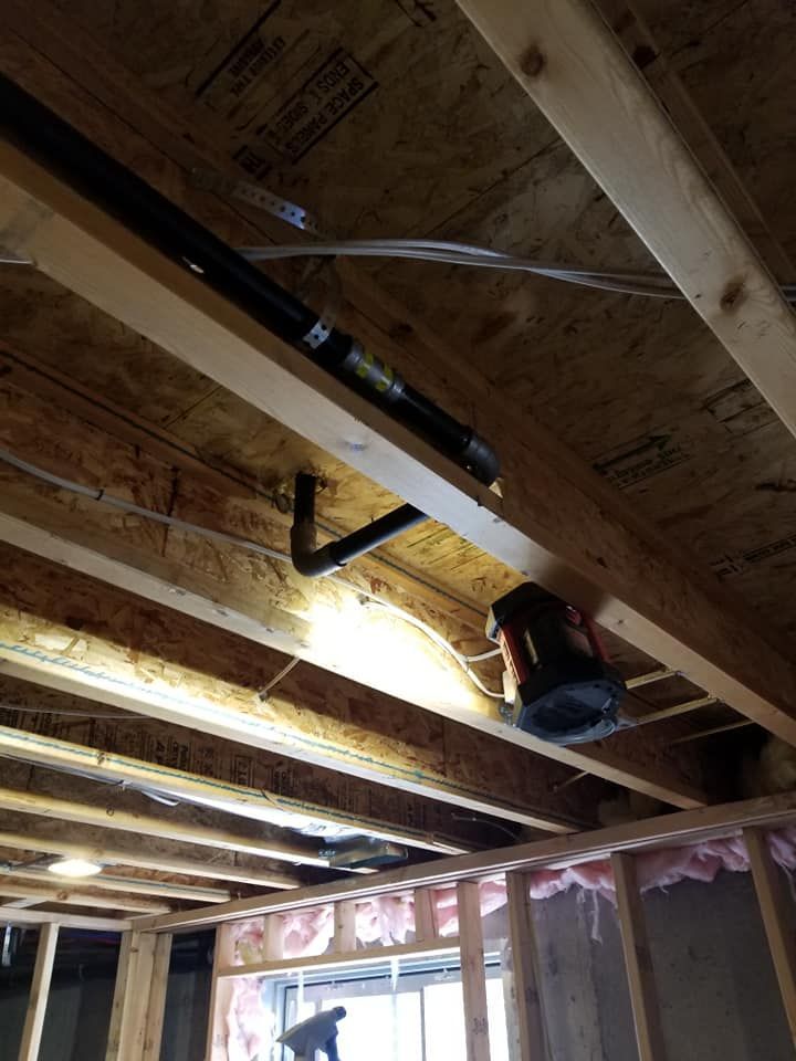 Basement ceiling framing with exposed joists, a hanging light, and a bucket on a beam.