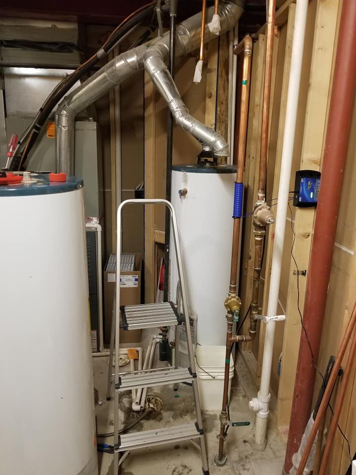 Utility room with water heater, furnace piping, and a small step stool beside exposed plumbing and ductwork