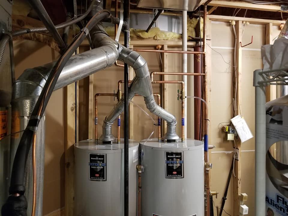 Basement with two water heaters and metal ducts in an unfinished utility room