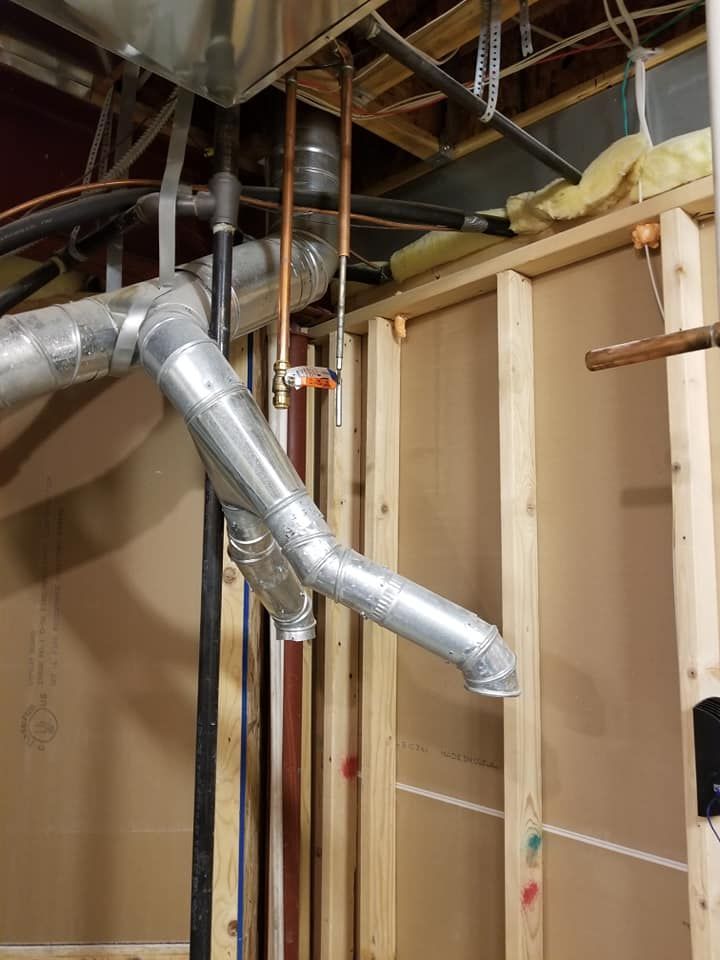 Basement construction with exposed wooden framing and silver HVAC ductwork against unfinished walls