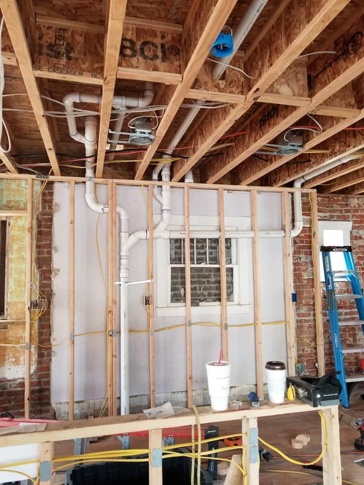 Unfinished room with exposed framing, insulation, ducts, and construction tools on the floor.