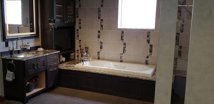 Modern bathroom with vanity, mirror, and a built-in tiled bathtub beneath a window.