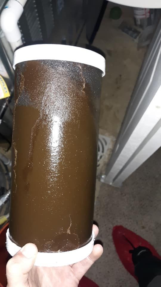 Hand holding a clear insulated tumbler filled with brown liquid near a doorway