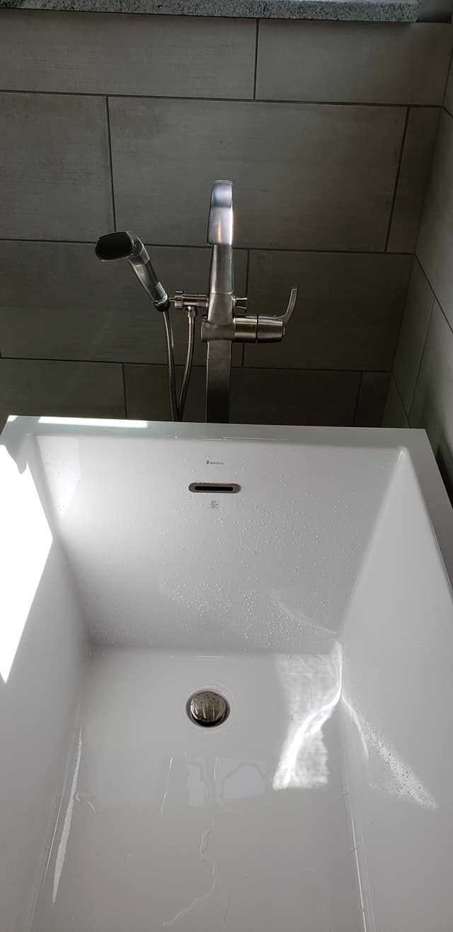 Modern white sink with chrome faucet against tiled wall