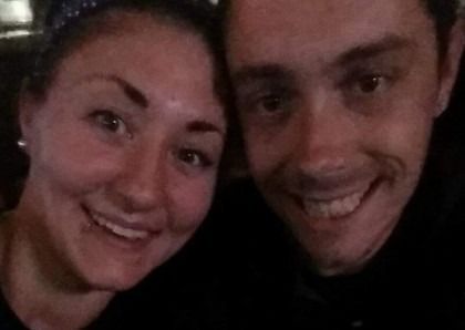 Two smiling people posing closely together in a dimly lit selfie