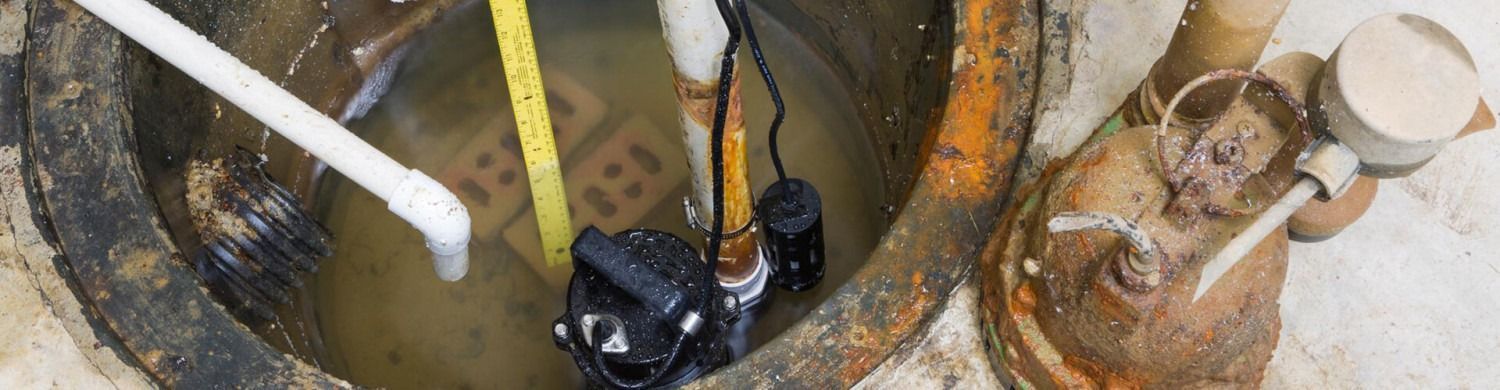 Overhead view of a rusted industrial pit with pipes, cables, and a white hose on the left.