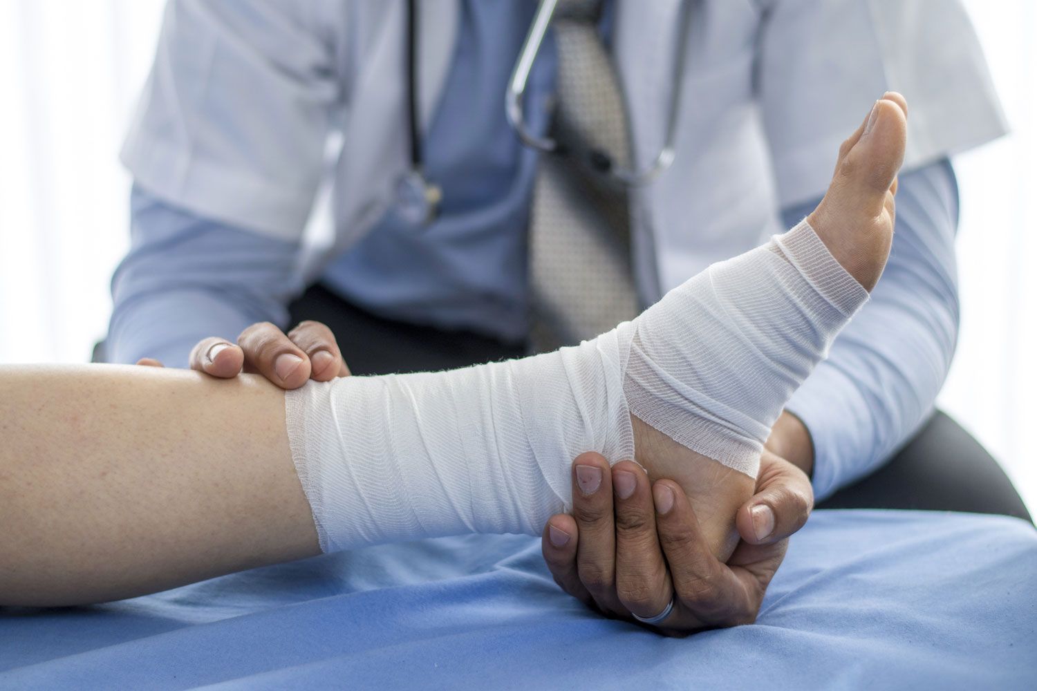 A doctor is wrapping a patient 's leg with a bandage.