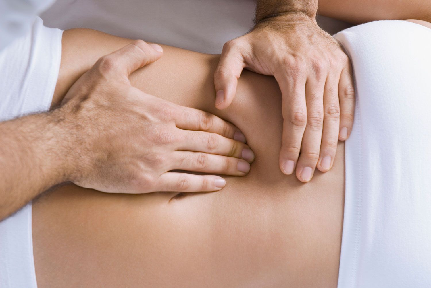 A man is giving a woman a massage on her stomach.