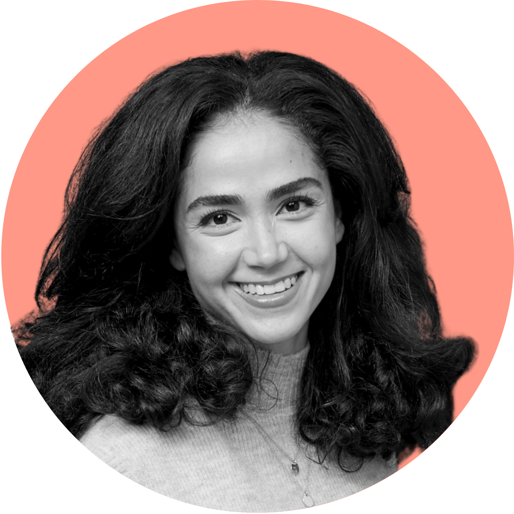 Woman with dark curly hair smiling, in a peach circle, wearing a gray turtleneck.