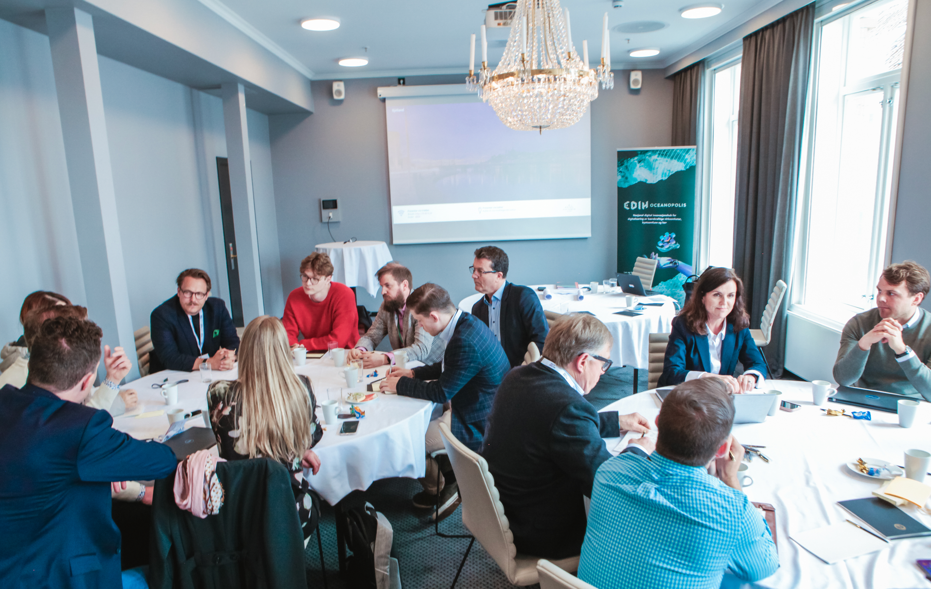 People seated around a large table in a meeting room, engaged in discussion.