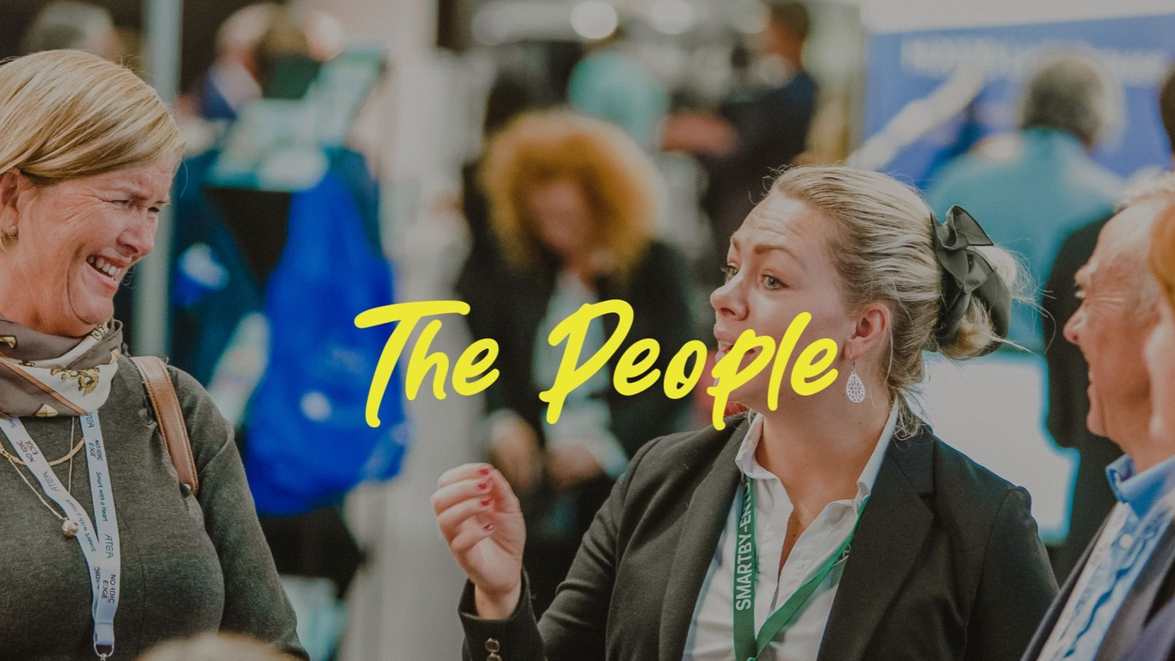People at an event, smiling and talking. Text overlay: 