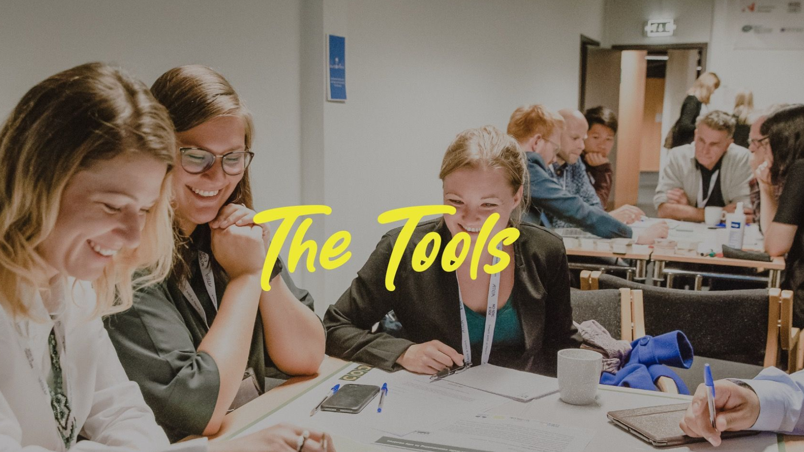 People at a table, smiling while looking at documents. Text 