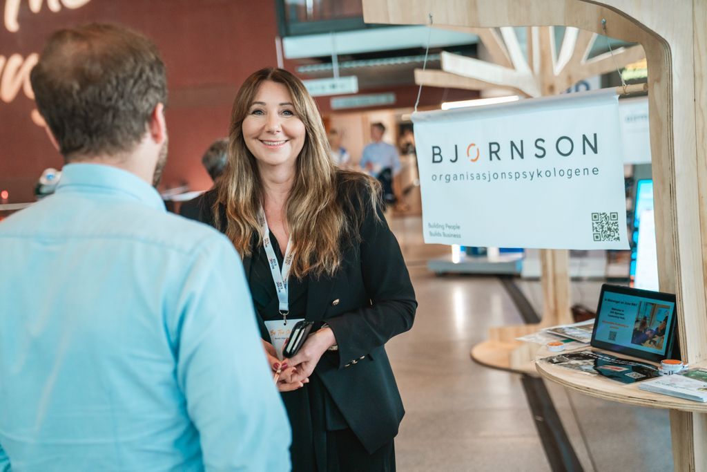 Woman smiles, talking to a man at a booth with a