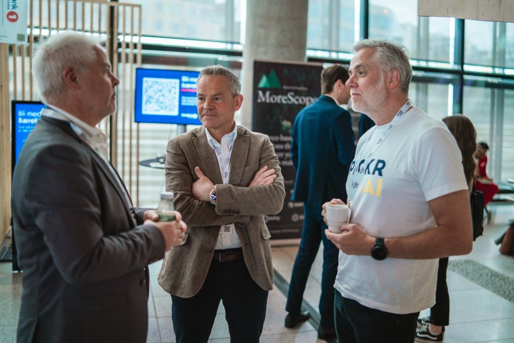Three men in suits and casual wear conversing at an event. A