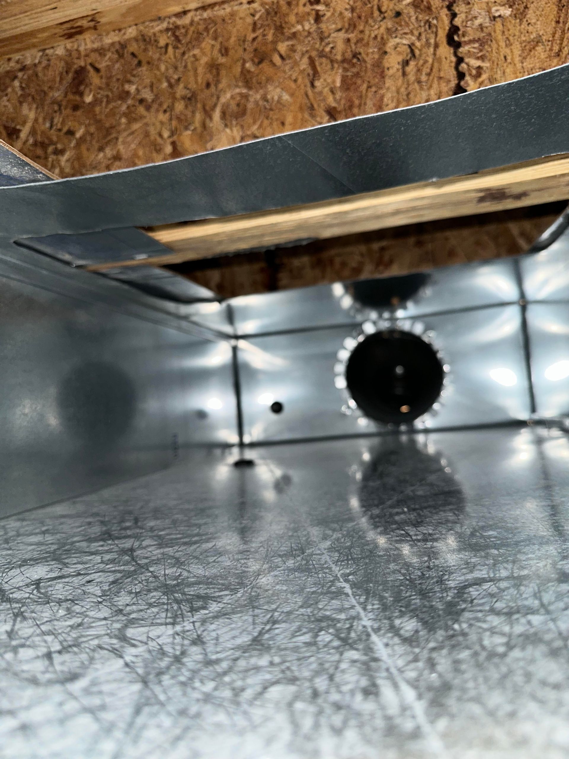 A close up of a metal duct with a hole in the middle.