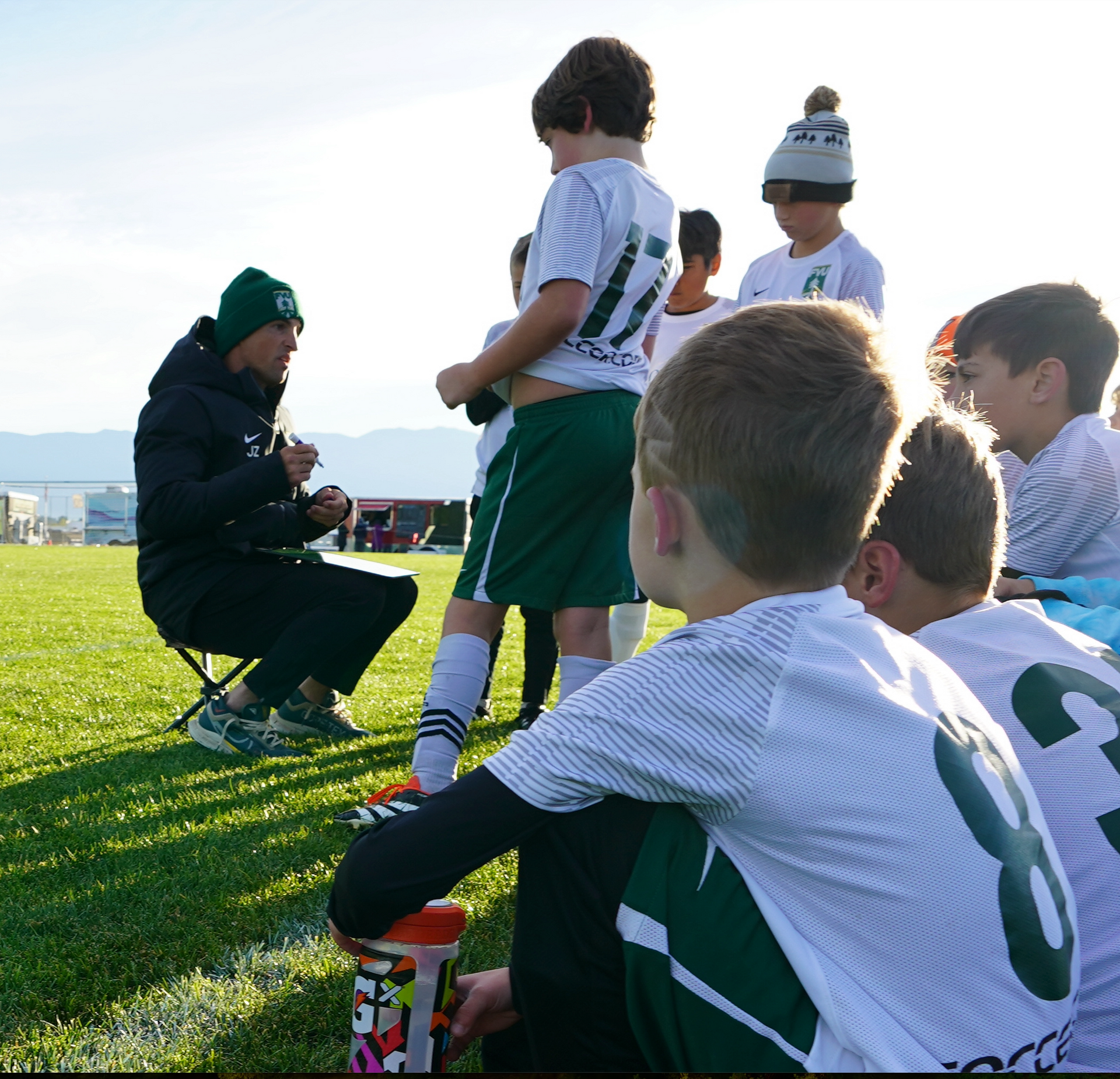 Young players listening attentively to their coach during a practice session, focusing on learning and team development.