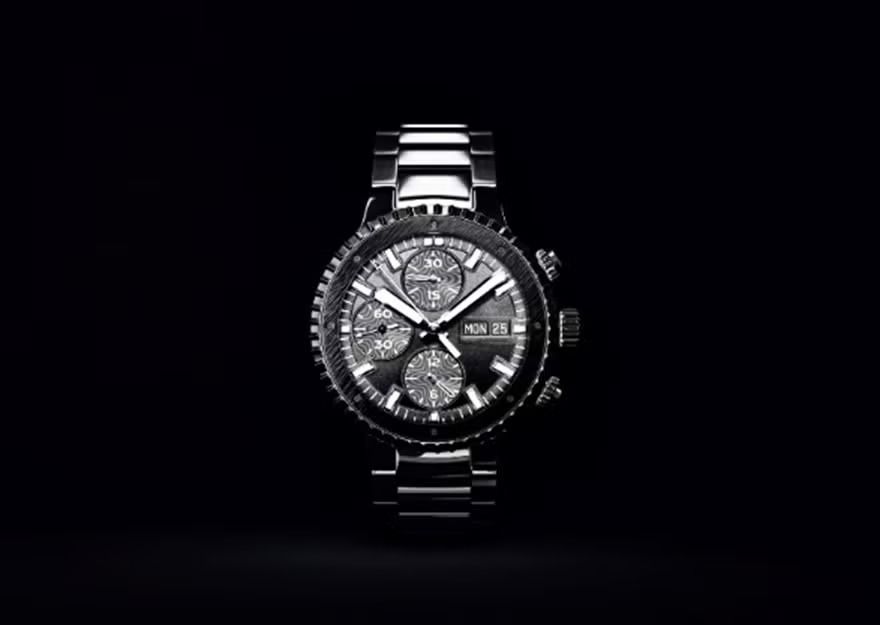 Silver chronograph wristwatch on a black background, centered and facing forward