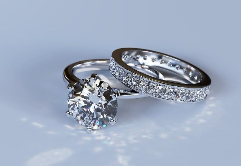 Two silver rings with a round diamond and small pavé stones on a light background