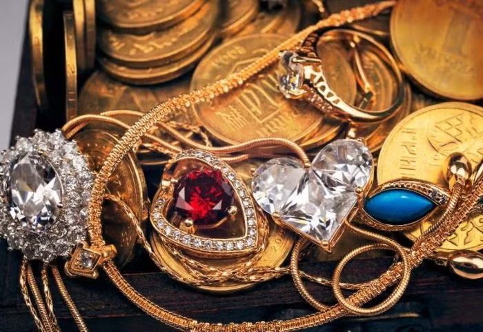 Assorted gold rings with gemstones, including red, clear, and blue stones, arranged in a jewelry display