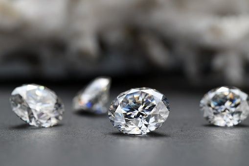 Three sparkling diamonds on a dark surface with a blurred background