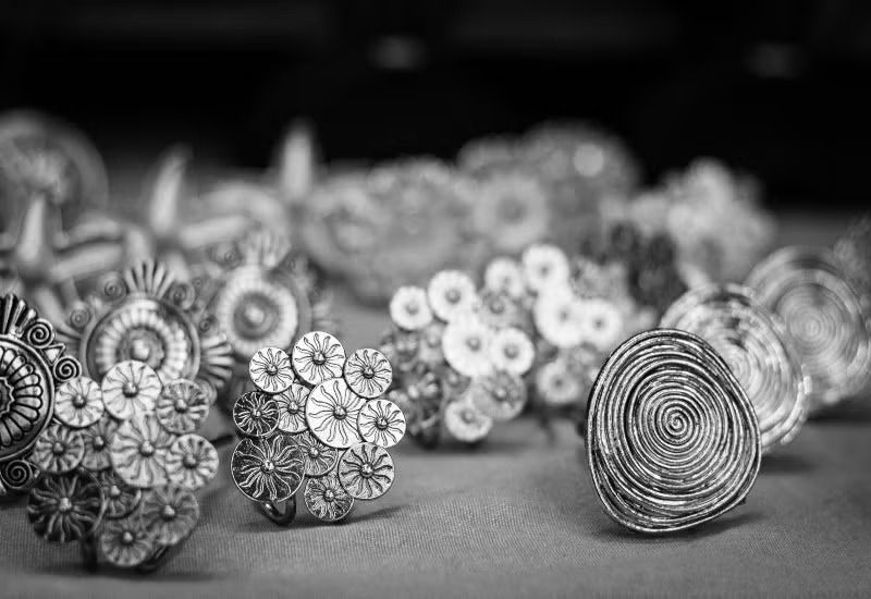 Black-and-white close-up of assorted intricate circular metal ornaments arranged on a surface
