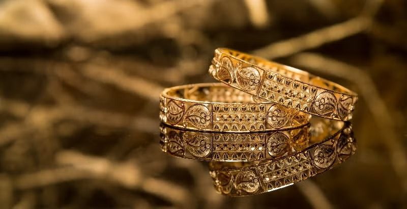 Gold filigree jewelry box with open lid on a warm brown background