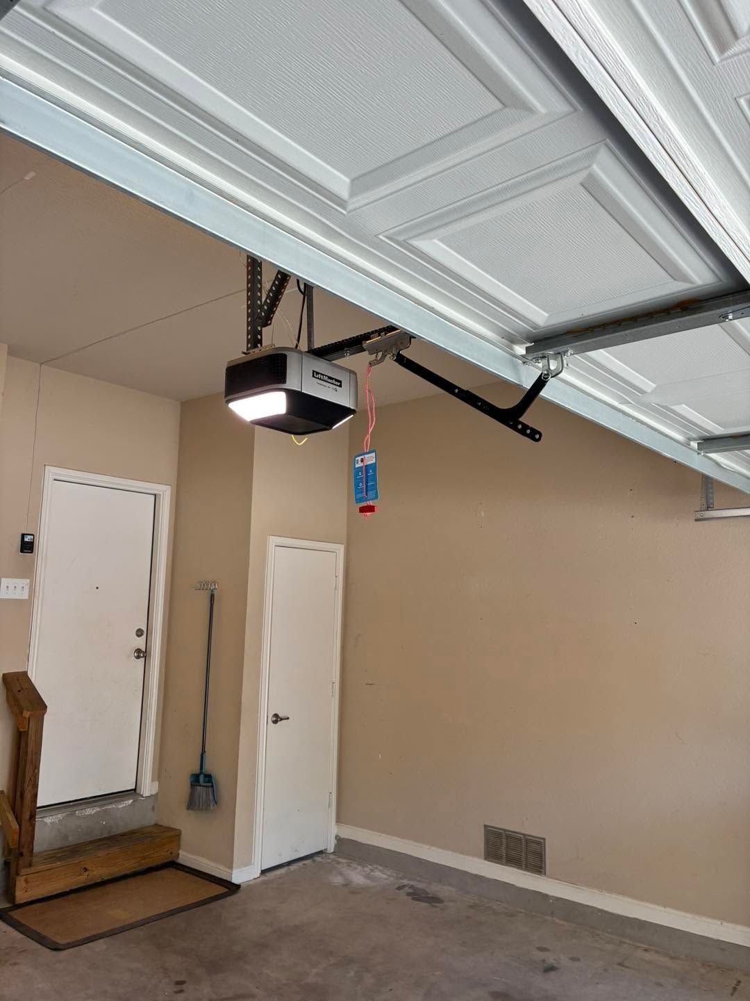 Open garage with white doors, beige walls, and a mounted garage door opener.