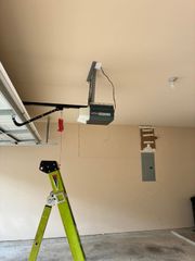 Garage ceiling with a green ladder and an overhead garage door opener mounted on a track.
