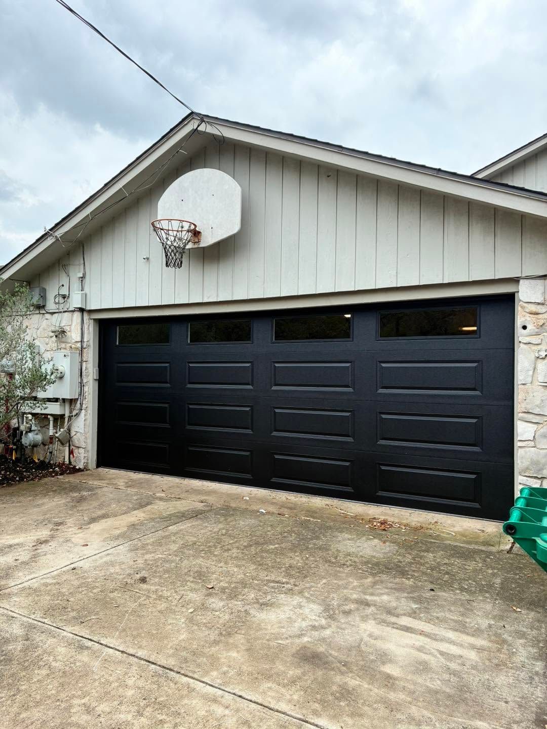House exterior with a black two-car garage and a basketball hoop mounted above the door