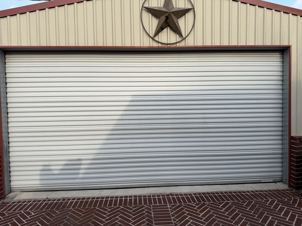 White roll-up garage door with a star emblem above it on a metal building.