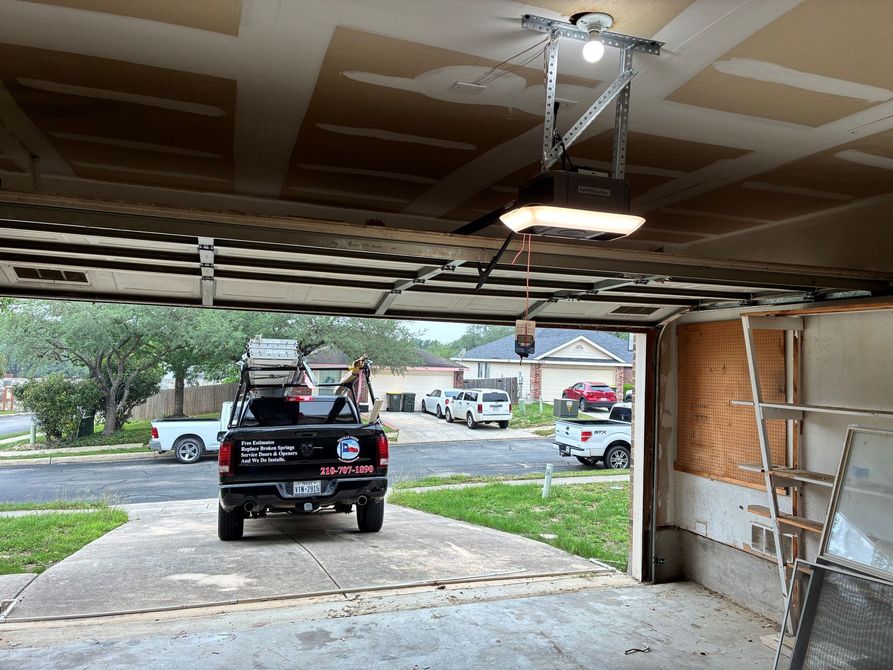Black pickup truck loaded with items in a driveway, viewed from inside a garage.