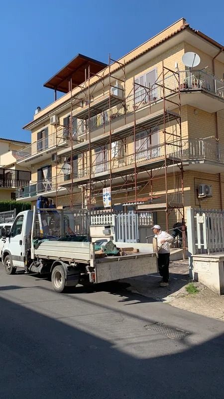 White utility truck parked by a beige apartment building with balconies on a sunny street
