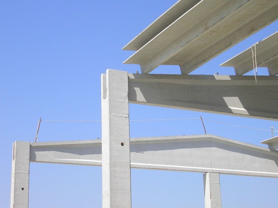 White structural beams against a blue sky with sunlight and a partial building frame