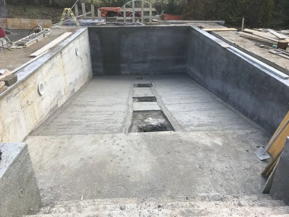 Empty concrete swimming pool under construction with a central drain channel