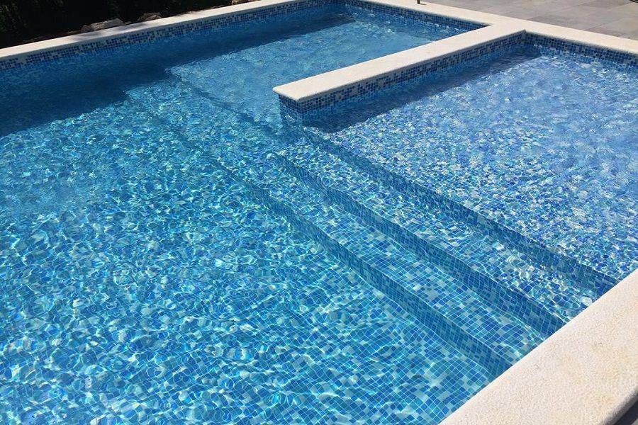 Blue swimming pool with clear water and a built-in shallow ledge or steps, viewed from above
