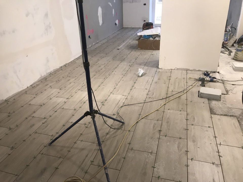 Renovation room with unfinished wood floor, tripod stand, and scattered building materials