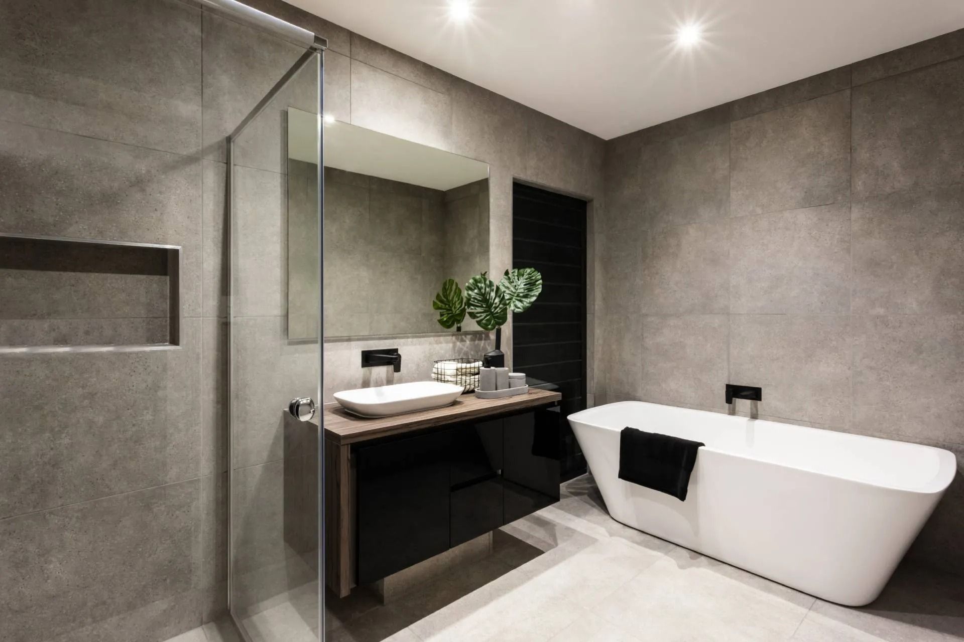 Modern gray bathroom with walk-in shower, floating vanity, large mirror, and freestanding bathtub