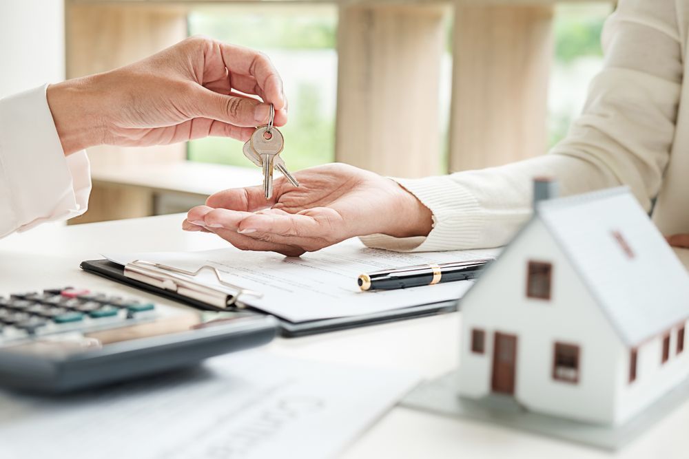 A Person Handing Keys to Another Person Over a Desk — Tenth Avenue Accountants & Financial Advisors in Cessnock, NSW