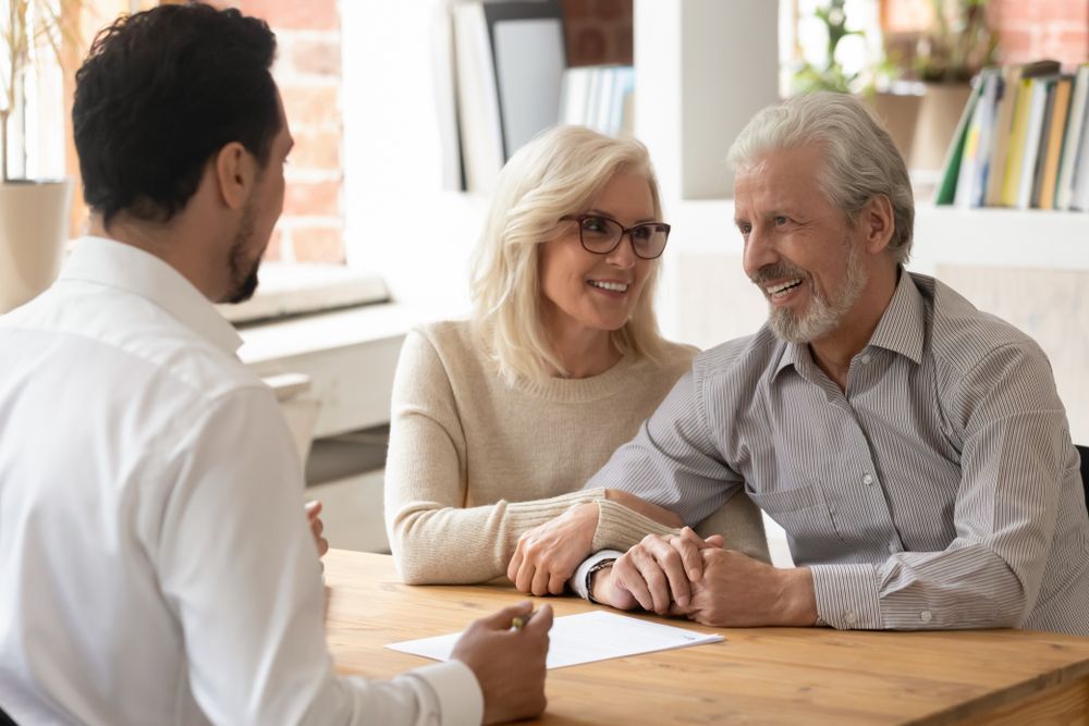 A Man Talking to an Elderly Couple Seated at a Table — Tenth Avenue Accountants & Financial Advisors in Toukley, NSW