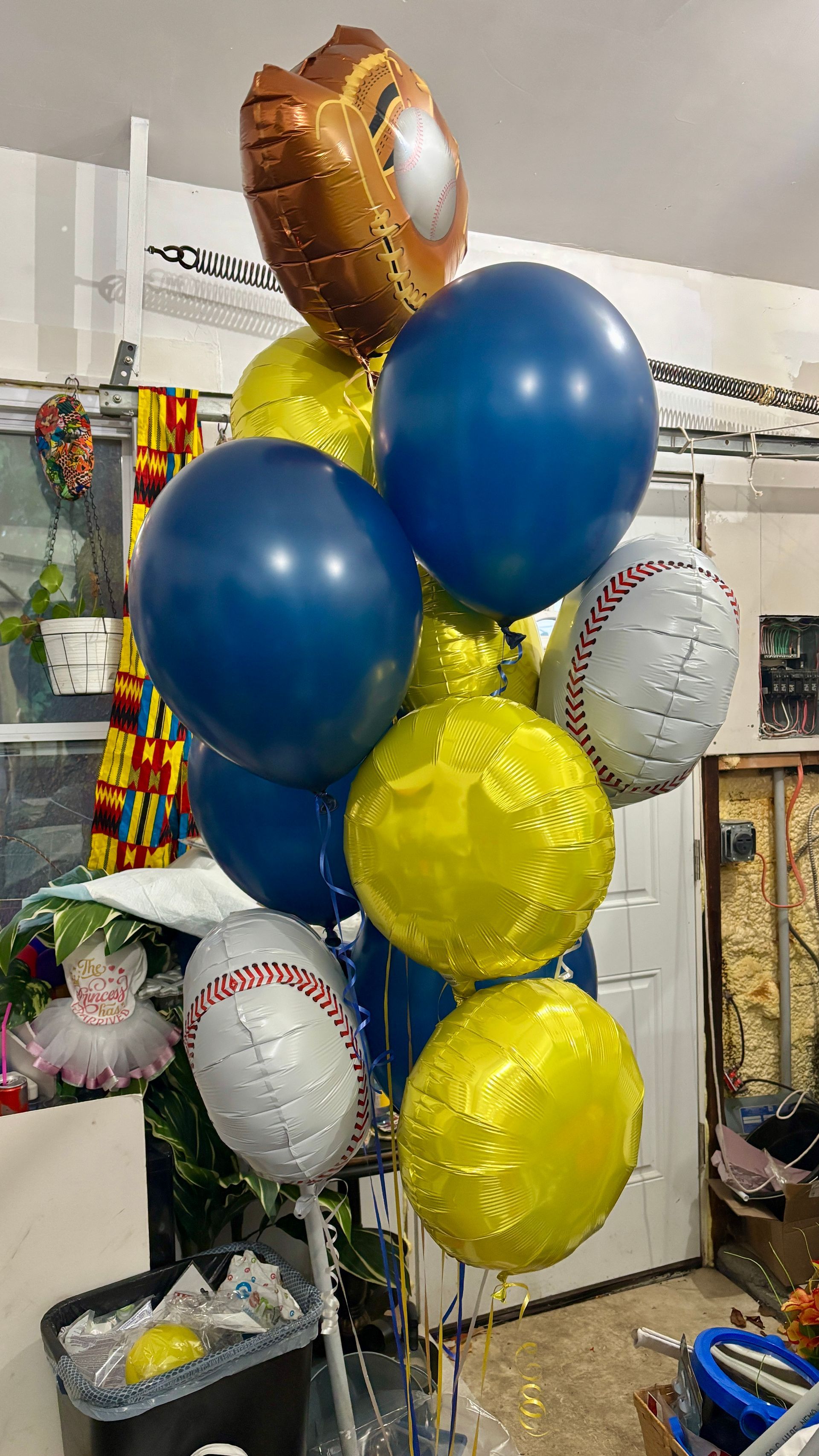 A bouquet of baseball-themed balloons, featuring blue, yellow, and baseball-shaped foil balloons.
