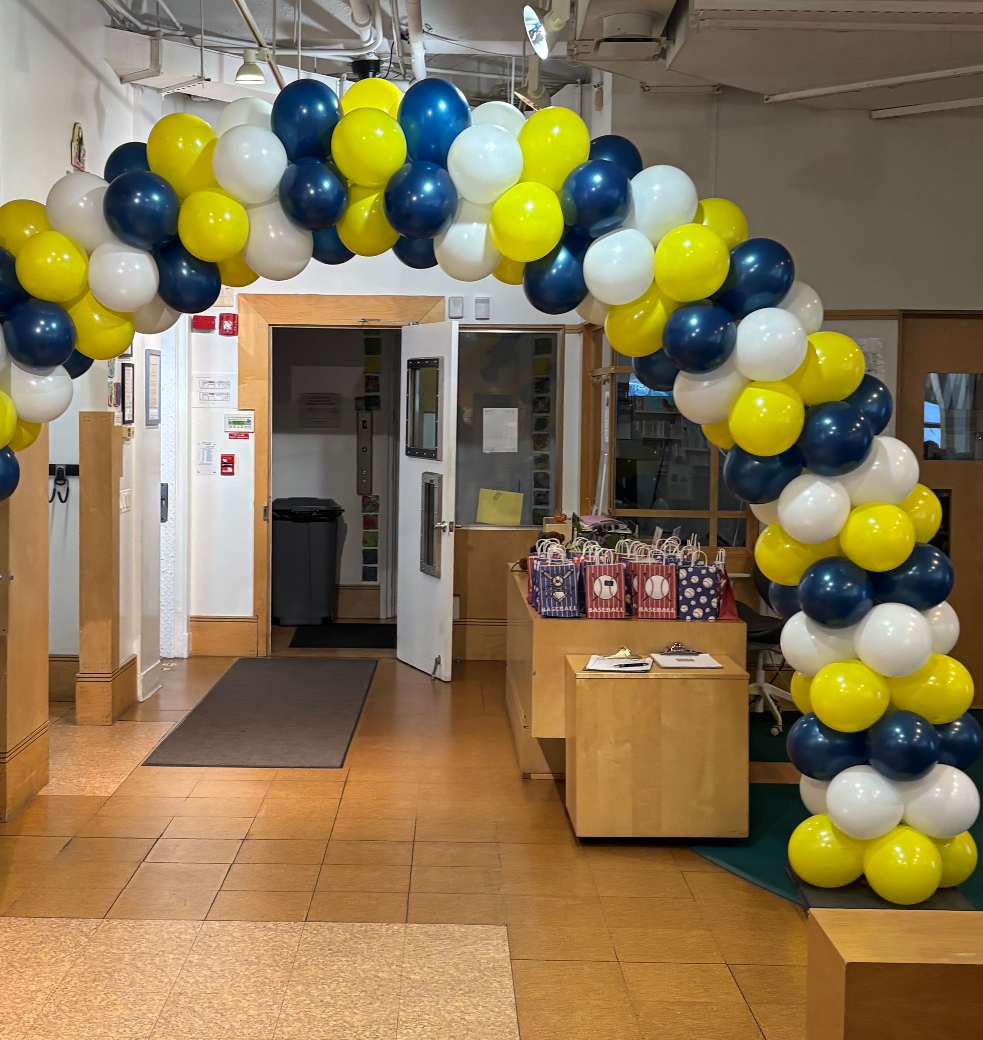 Archway of yellow, blue, and white balloons over a doorway.