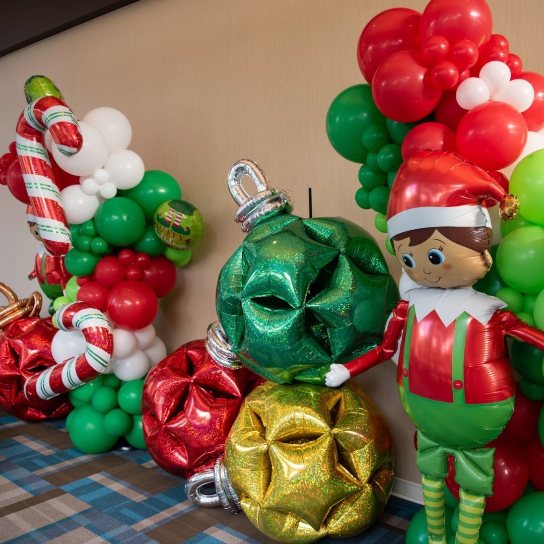 Festive balloon decorations featuring Christmas ornaments, an elf, and candy canes.