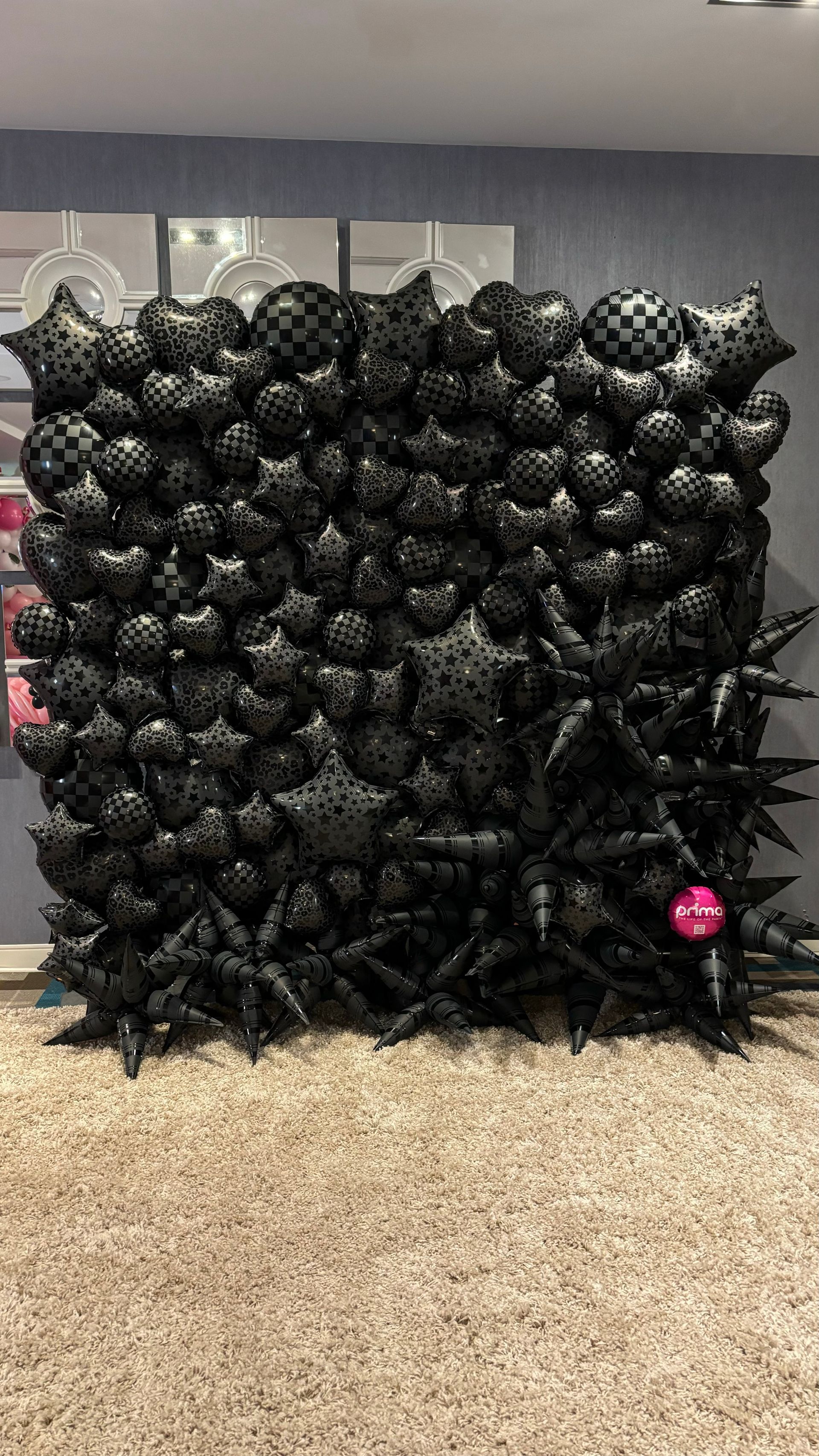 Black balloon wall with stars and checkered balloons.