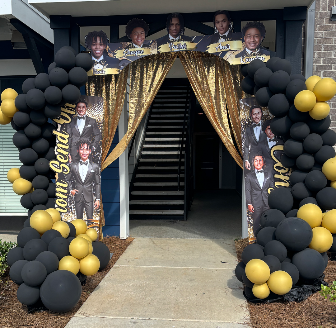Black and gold balloon archway framing an entry decorated for a graduation send-off.