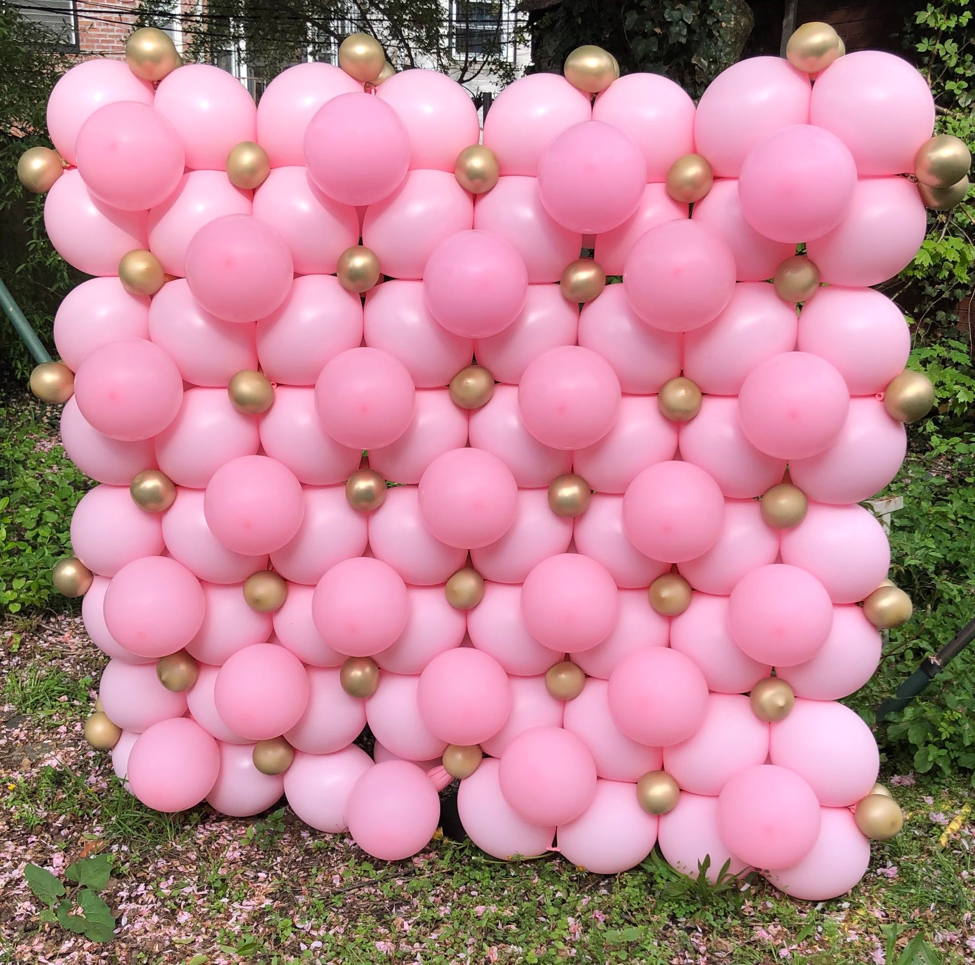 Pink and gold balloon wall, outdoor setting.