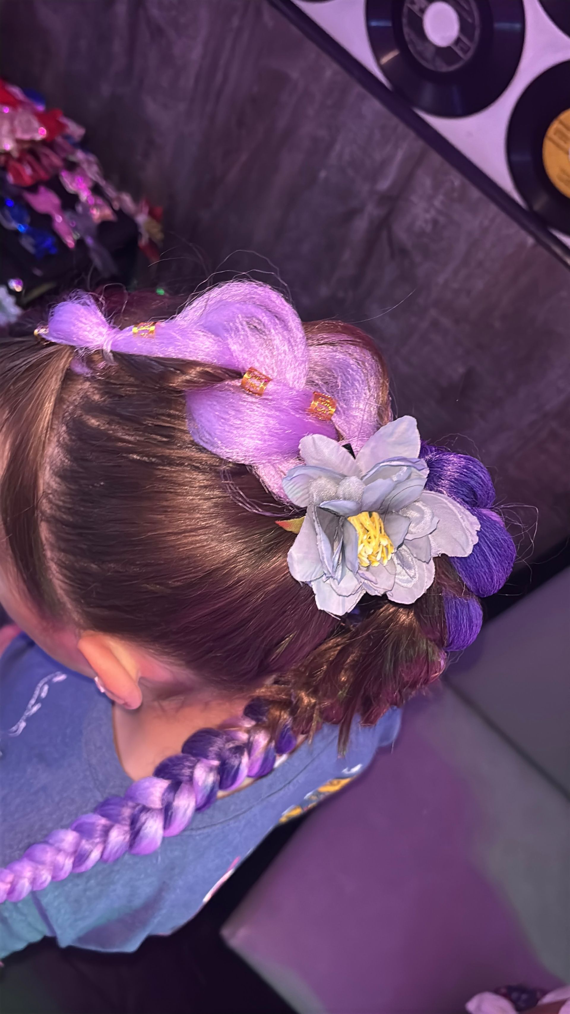 Purple braided hairstyle with a flower accent.